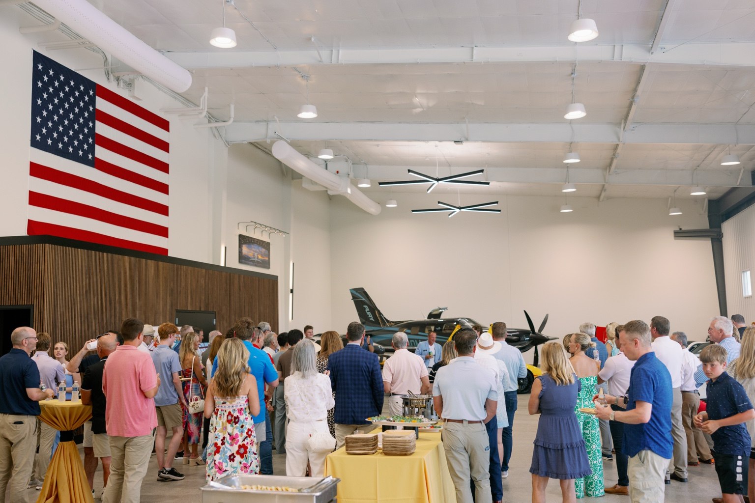 Guests mingling inside the bright event hangar