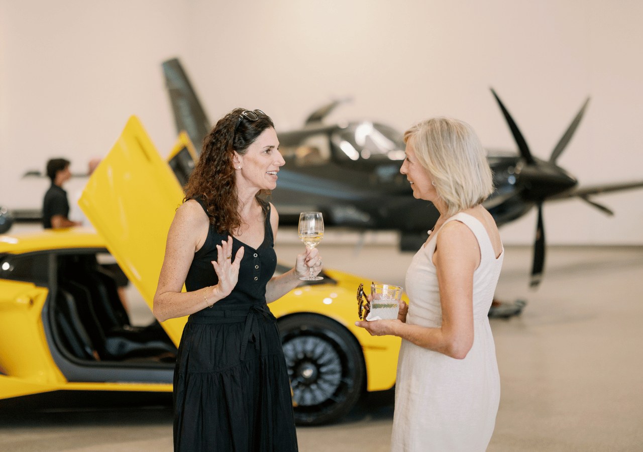 Guests chatting beside a sports car and aircraft