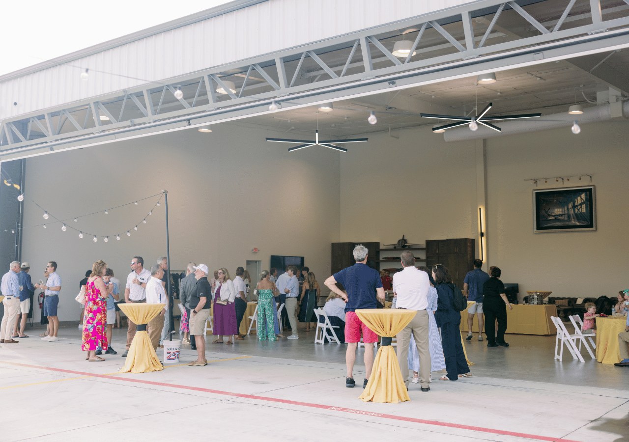 Guests gathering inside the bright, open event hangar at Spirit Sky Club